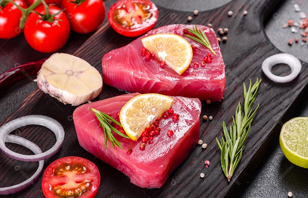 Bifes de filé de atum fresco com especiarias e ervas sobre fundo preto. Preparando atum para assar