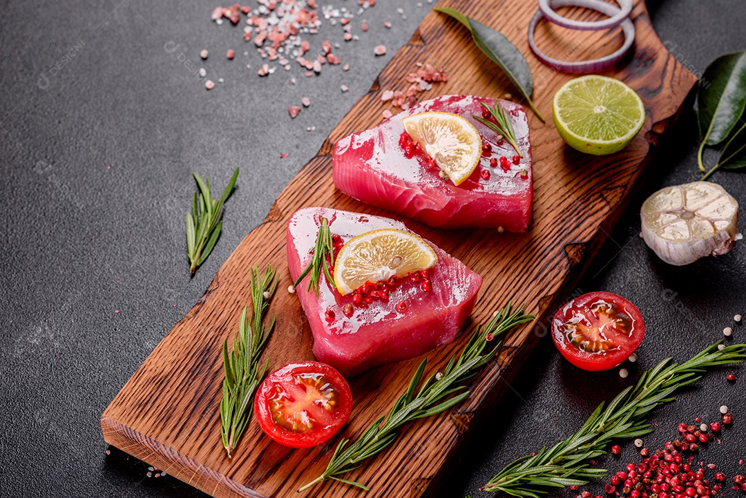Bifes de filé de atum fresco com especiarias e ervas sobre fundo preto. Preparando atum para assar