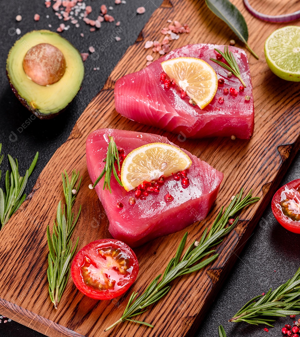 Bifes de filé de atum fresco com especiarias e ervas sobre fundo preto. Preparando atum para assar