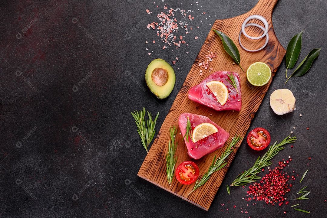 Bifes de filé de atum fresco com especiarias e ervas sobre fundo preto. Preparando atum para assar