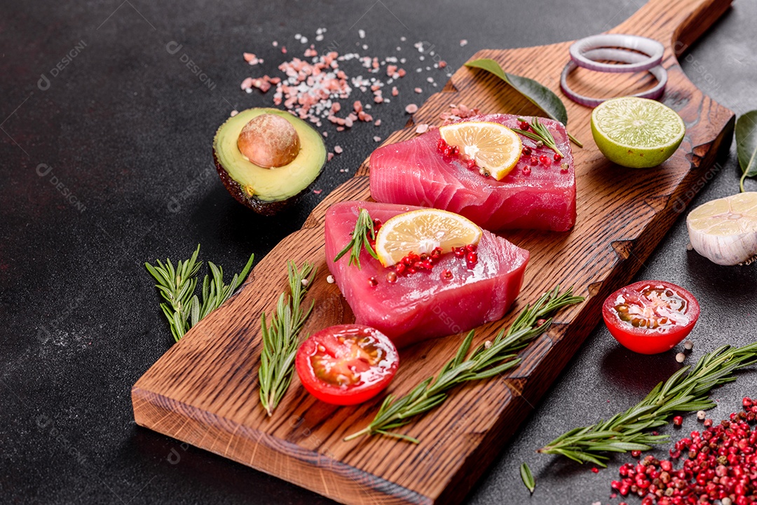 Bifes de filé de atum fresco com especiarias e ervas sobre fundo preto. Preparando atum para assar