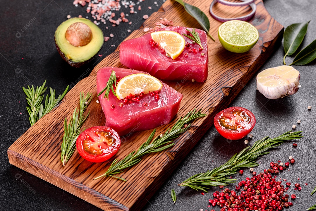 Bifes de filé de atum fresco com especiarias e ervas sobre fundo preto. Preparando atum para assar