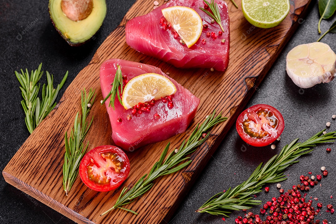 Bifes de filé de atum fresco com especiarias e ervas sobre fundo preto. Preparando atum para assar