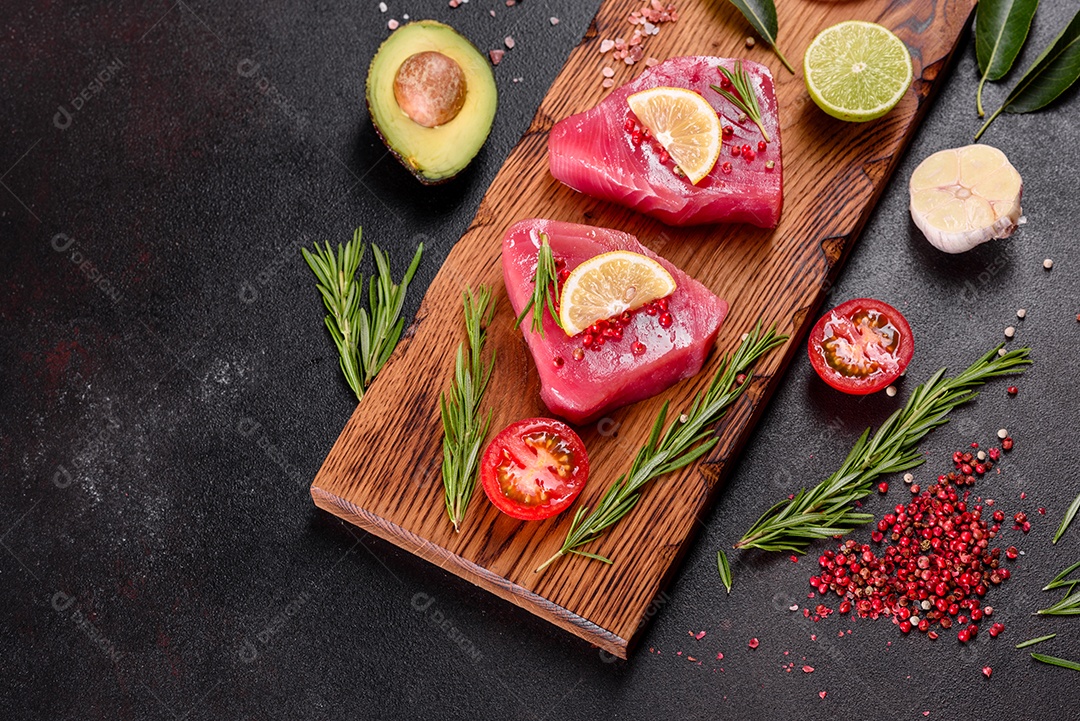 Bifes de filé de atum fresco com especiarias e ervas sobre fundo preto. Preparando atum para assar