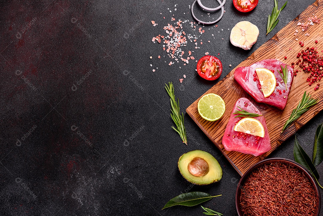 Bifes de filé de atum fresco com especiarias e ervas sobre fundo preto. Preparando atum para assar