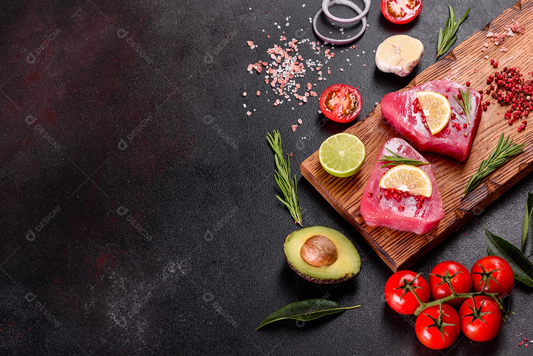 Bifes de filé de atum fresco com especiarias e ervas sobre fundo preto. Preparando atum para assar
