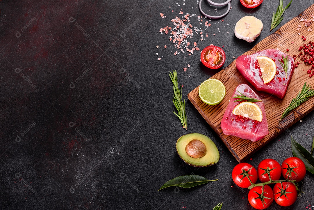 Bifes de filé de atum fresco com especiarias e ervas sobre fundo preto. Preparando atum para assar