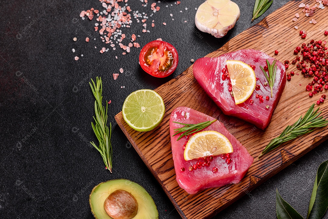 Bifes de filé de atum fresco com especiarias e ervas sobre fundo preto. Preparando atum para assar