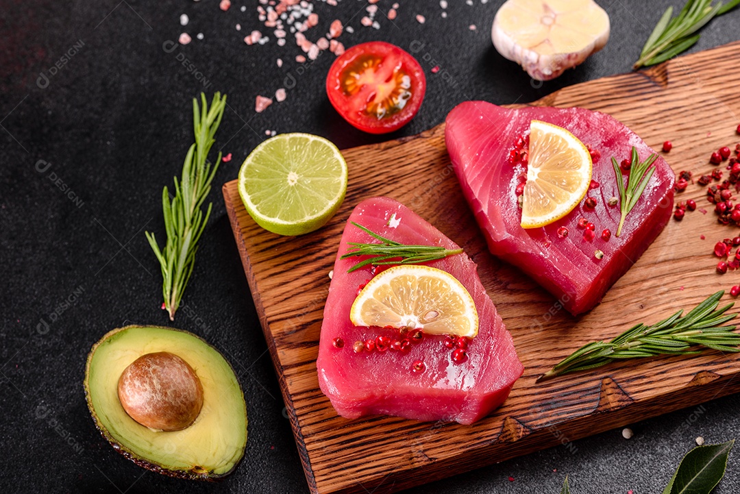 Bifes de filé de atum fresco com especiarias e ervas sobre fundo preto. Preparando atum para assar