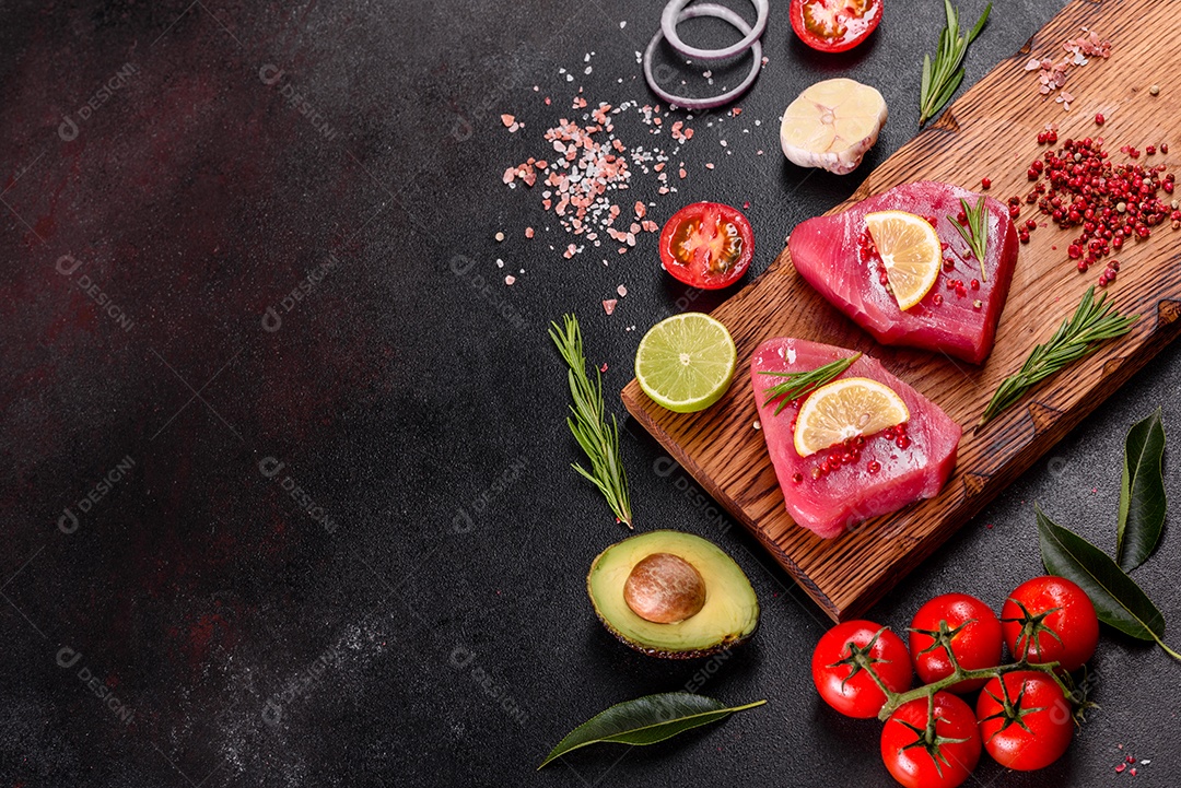 Bifes de filé de atum fresco com especiarias e ervas sobre fundo preto. Preparando atum para assar