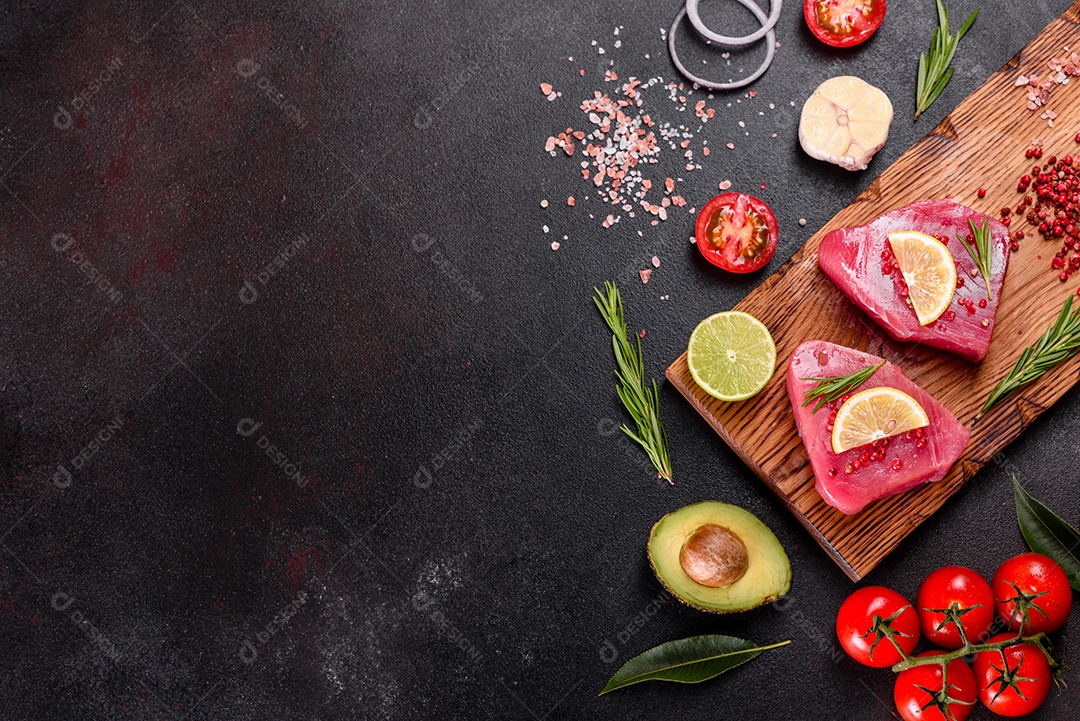 Bifes de filé de atum fresco com especiarias e ervas sobre fundo preto. Preparando atum para assar
