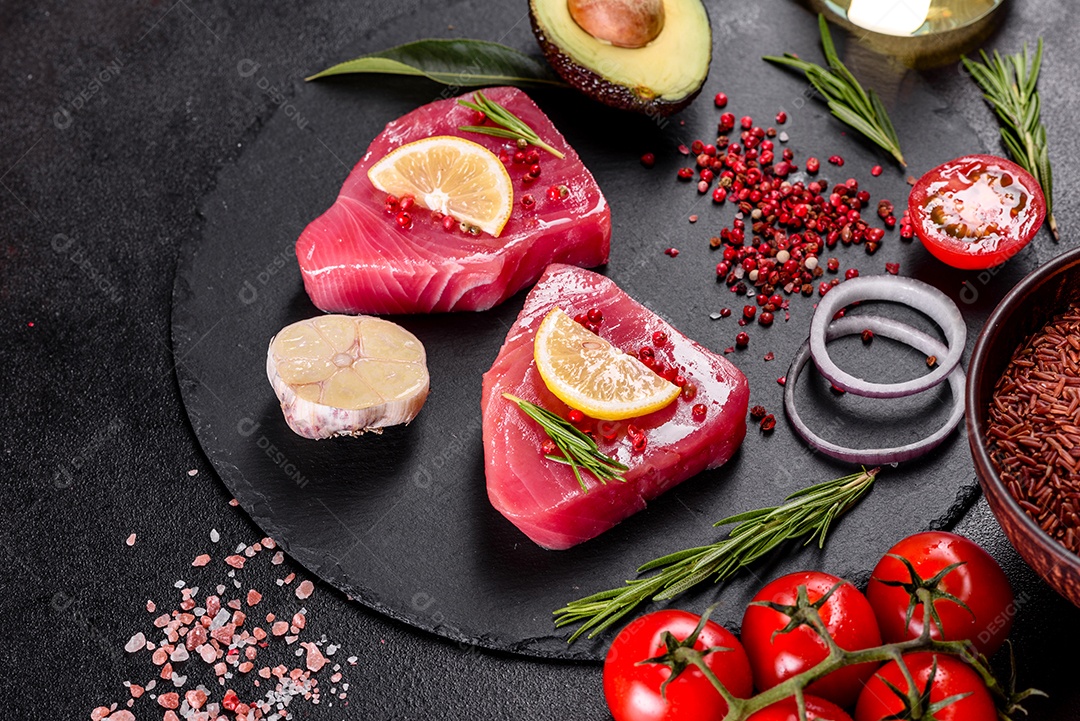 Bifes de filé de atum fresco com especiarias e ervas sobre fundo preto. Preparando atum para assar