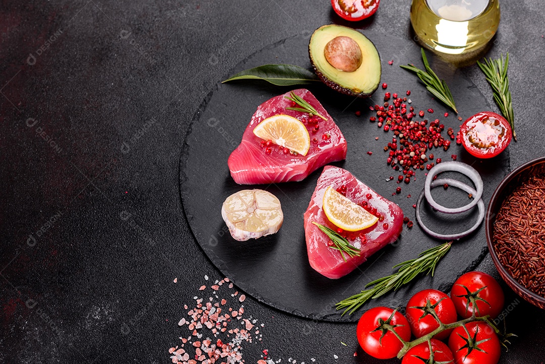 Bifes de filé de atum fresco com especiarias e ervas sobre fundo preto. Preparando atum para assar