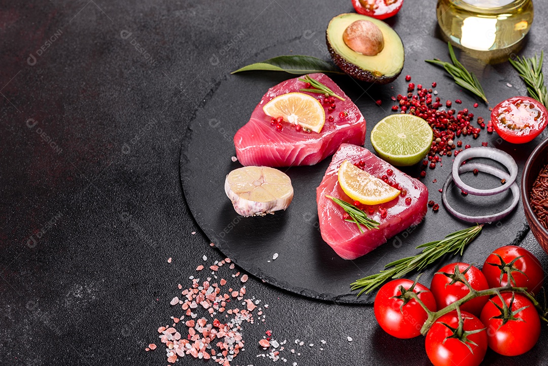 Bifes de filé de atum fresco com especiarias e ervas sobre fundo preto.