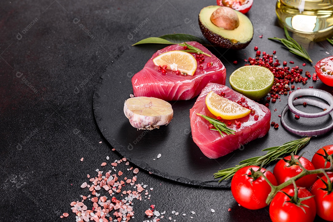 Bifes de filé de atum fresco com especiarias e ervas sobre fundo preto.