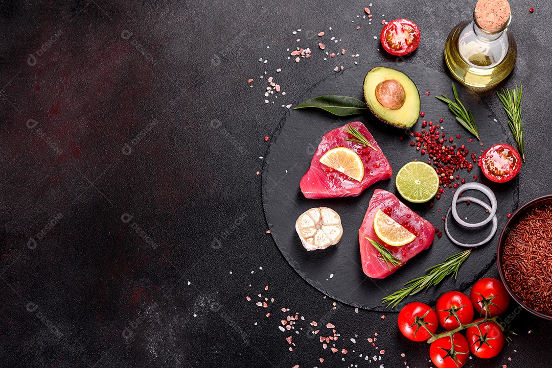 Bifes de filé de atum fresco com especiarias e ervas sobre fundo preto.