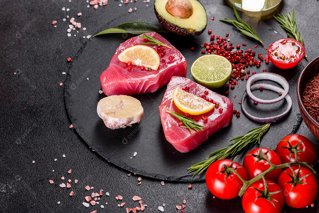 Bifes de filé de atum fresco com especiarias e ervas sobre fundo preto.