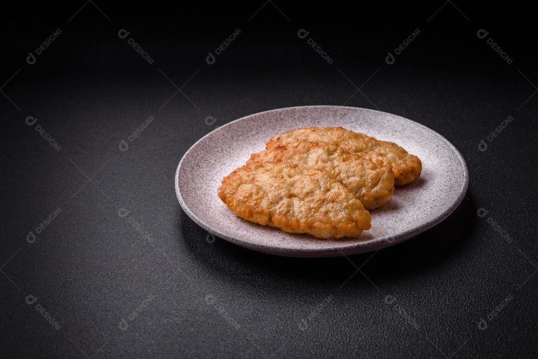 Deliciosos peixes picados fritos frescos ou costeletas de frango com especiarias e ervas sobre um fundo escuro de concreto