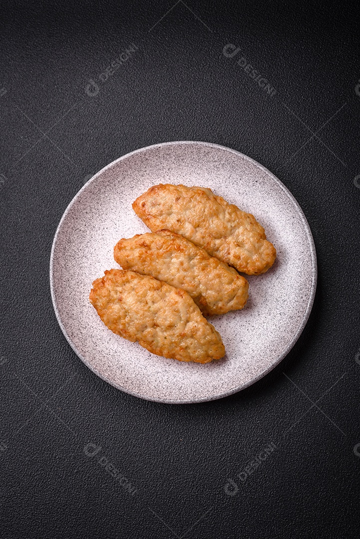 Deliciosos peixes picados fritos frescos ou costeletas de frango com especiarias e ervas sobre um fundo escuro de concreto
