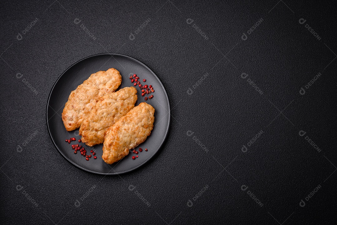 Deliciosos peixes picados fritos frescos ou costeletas de frango com especiarias e ervas sobre um fundo escuro de concreto