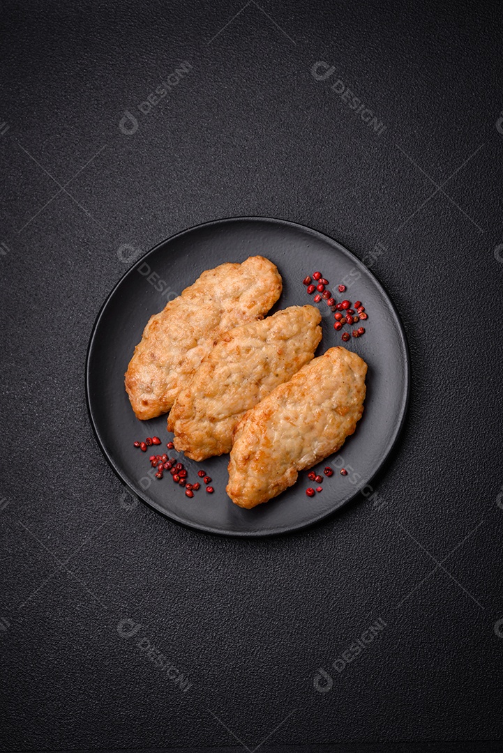 Deliciosos peixes picados fritos frescos ou costeletas de frango com especiarias e ervas sobre um fundo escuro de concreto