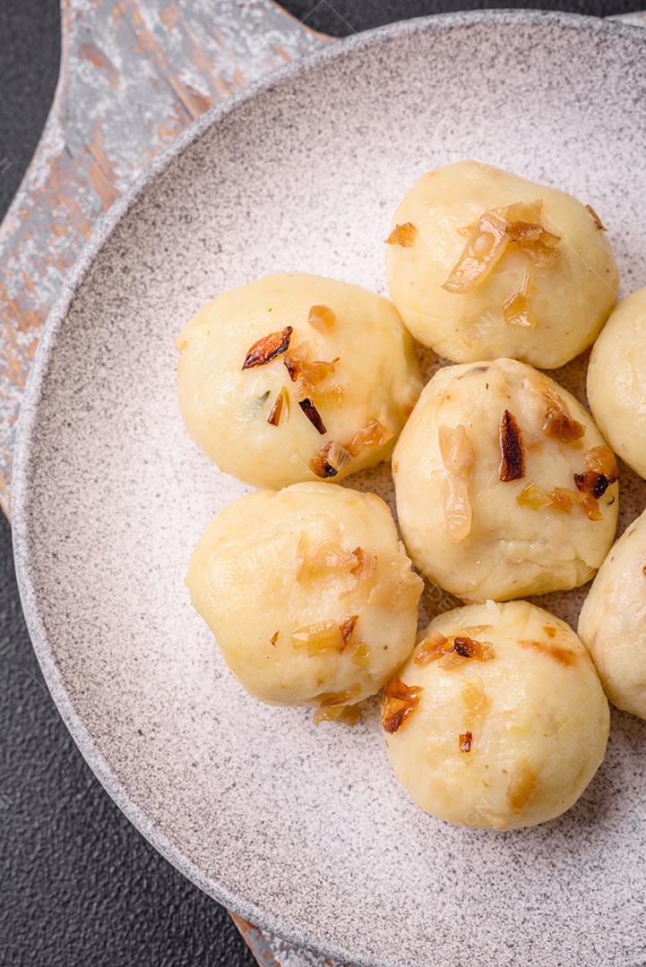 Deliciosos bolinhos caseiros cozidos frescos com queijo, batatas e sal num prato cerâmico