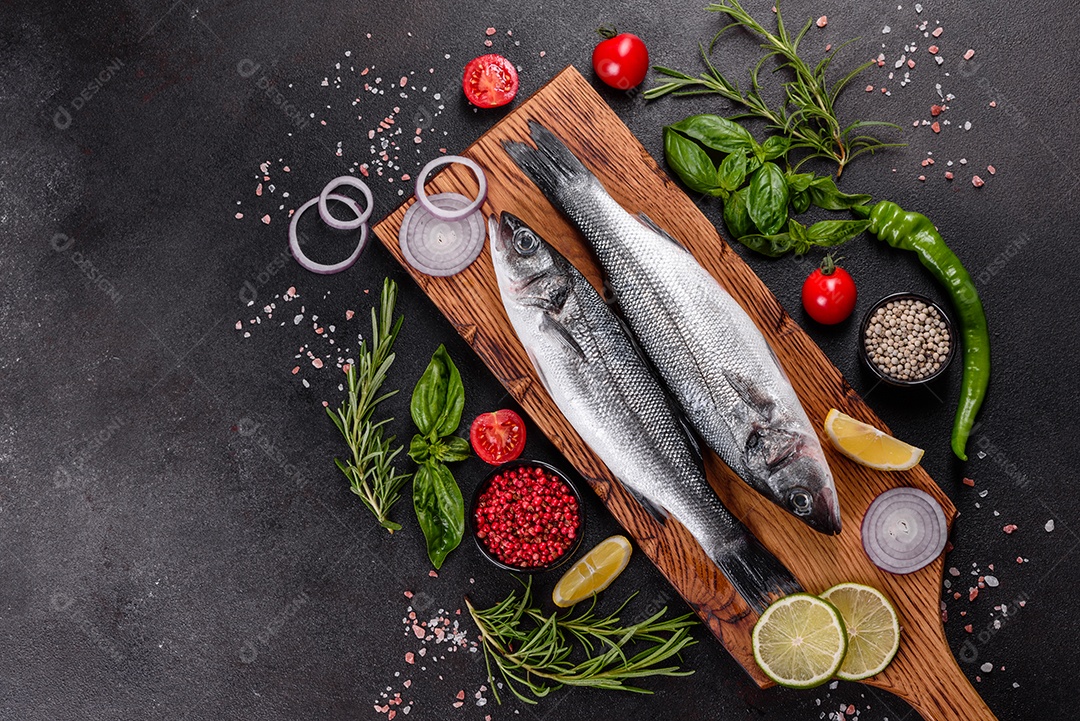 Robalo de peixe fresco e ingredientes para cozinhar. Robalo de peixe cru com especiarias e ervas em uma mesa escura