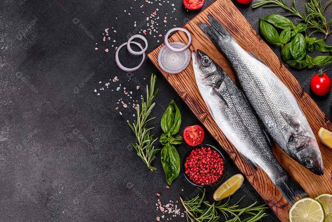 Robalo de peixe fresco e ingredientes para cozinhar. Robalo de peixe cru com especiarias e ervas em uma mesa escura