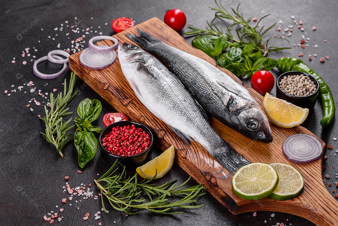 Robalo de peixe fresco e ingredientes para cozinhar. Robalo de peixe cru com especiarias e ervas em uma mesa escura