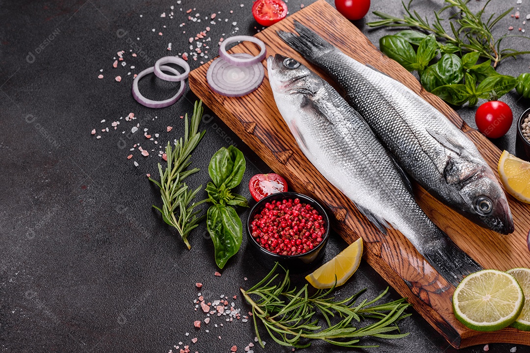 Robalo de peixe fresco e ingredientes para cozinhar. Robalo de peixe cru com especiarias e ervas em uma mesa escura