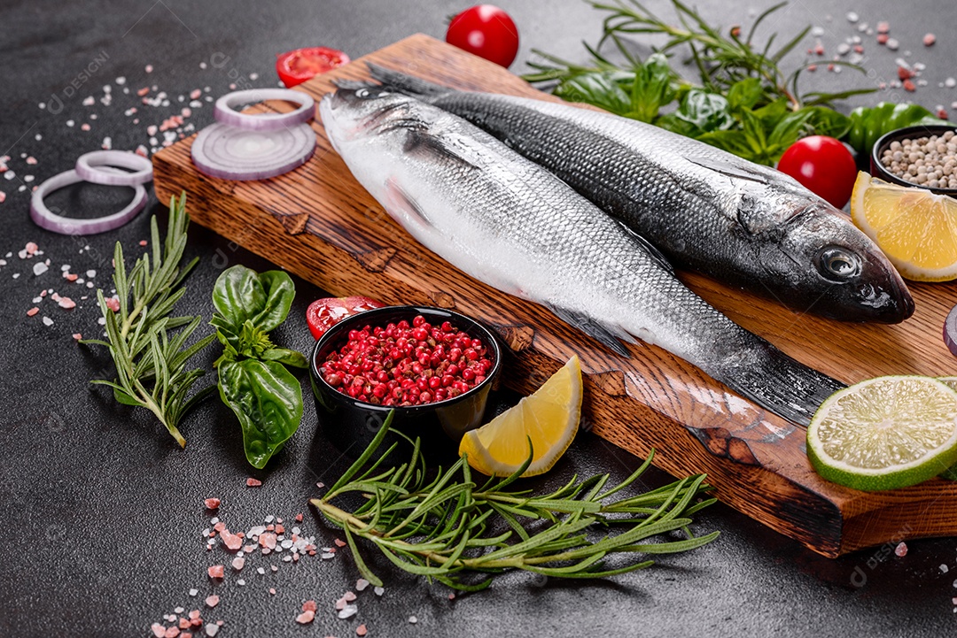 Robalo de peixe fresco e ingredientes para cozinhar. Robalo de peixe cru com especiarias e ervas em uma mesa escura