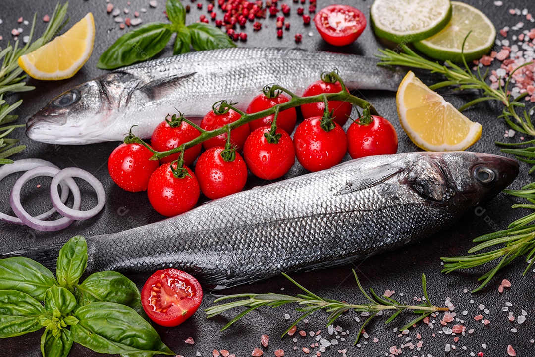 Robalo de peixe fresco e ingredientes para cozinhar. Robalo de peixe cru com especiarias e ervas em uma mesa escura