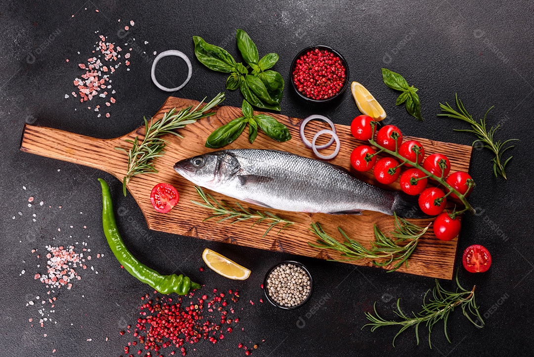 Robalo de peixe fresco e ingredientes para cozinhar. Robalo de peixe cru com especiarias e ervas em uma mesa escura