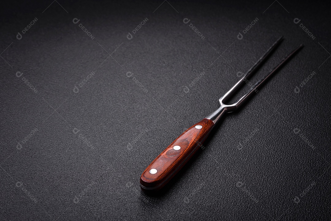 Garfo de cozinha feitos de aço em um fundo escuro de concreto