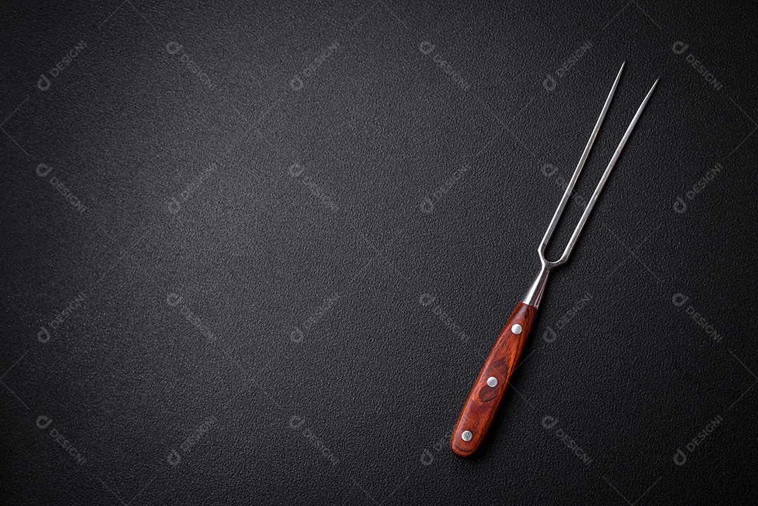 Garfo de cozinha feitos de aço em um fundo escuro de concreto