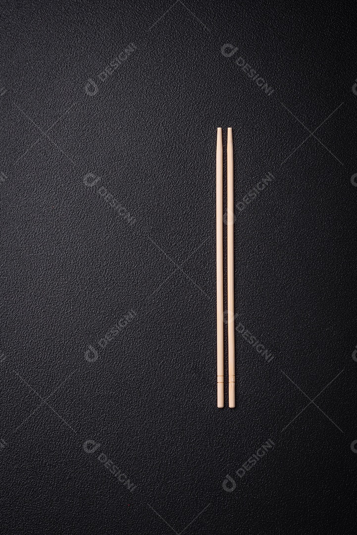 Pauzinhos de madeira brancos para pratos asiáticos em um fundo escuro de concreto