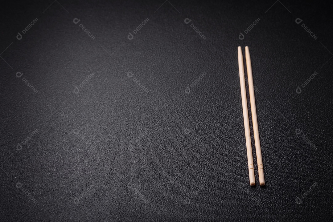 Pauzinhos de madeira brancos para pratos asiáticos em um fundo escuro de concreto