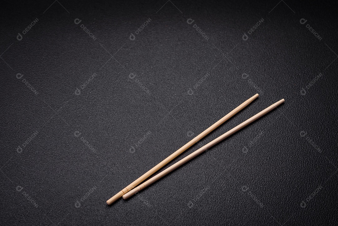 Pauzinhos de madeira brancos para pratos asiáticos em um fundo escuro de concreto