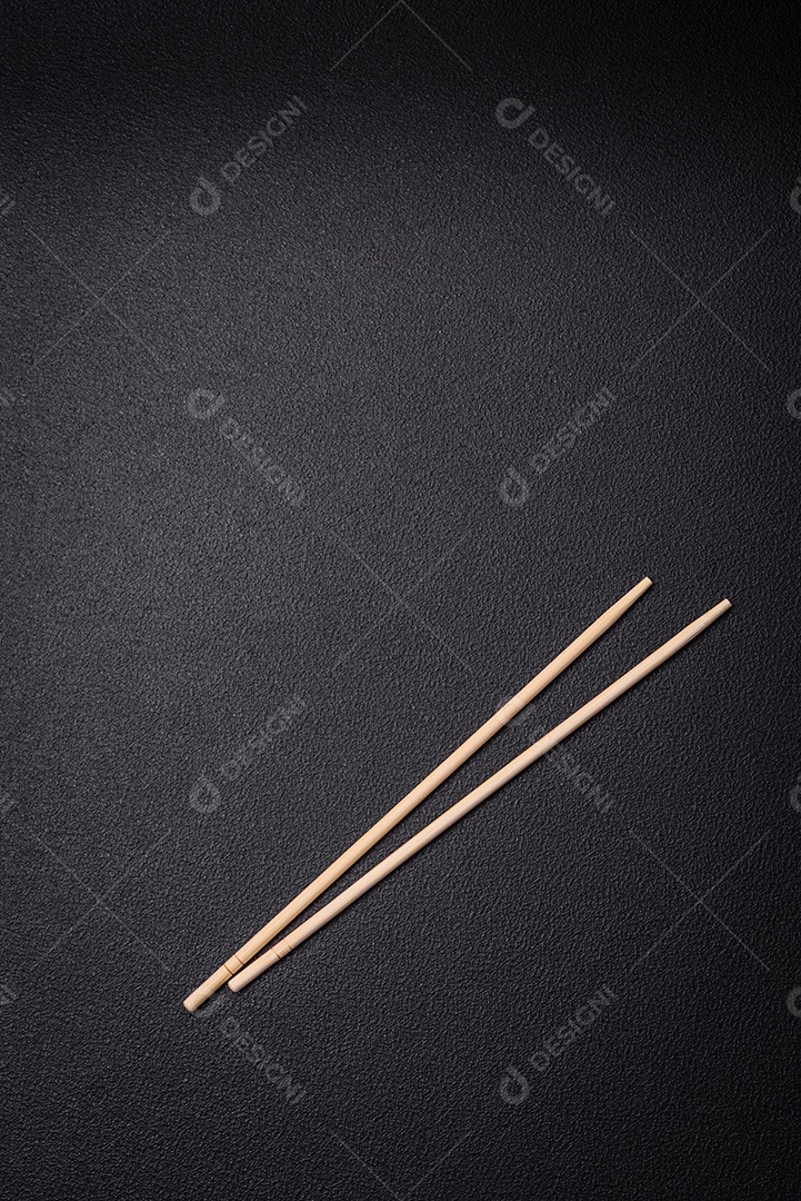 Pauzinhos de madeira brancos para pratos asiáticos em um fundo escuro de concret