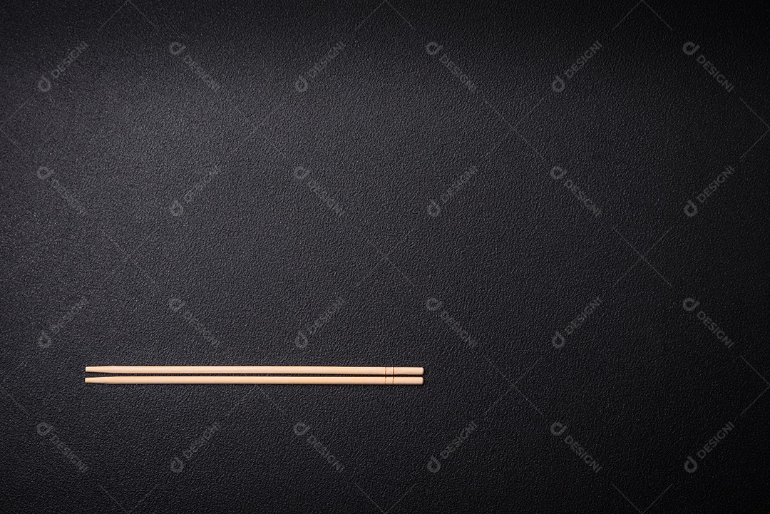 Pauzinhos de madeira brancos para pratos asiáticos em um fundo escuro de concreto