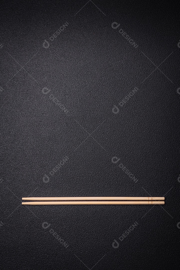 Pauzinhos de madeira brancos para pratos asiáticos em um fundo escuro de concreto