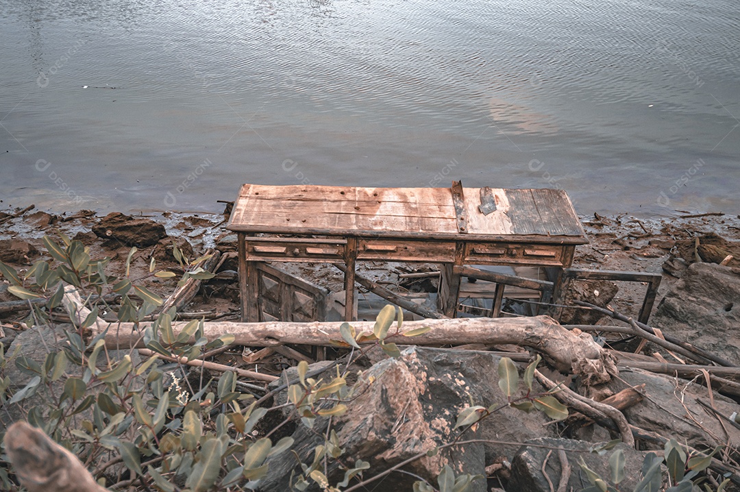 Móveis de madeira jogados à beira-mar na maré baixa, lixo no mar