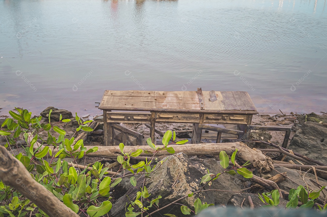 Móveis de madeira jogados à beira-mar na maré baixa, lixo no mar