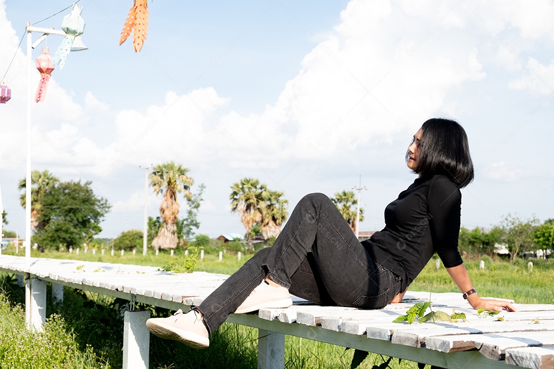 Uma garota de cabelos curtos sentada sobre ponte de madeira