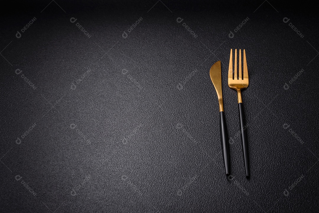 Faca e garfo de cozinha feitos de aço em um fundo escuro de concreto