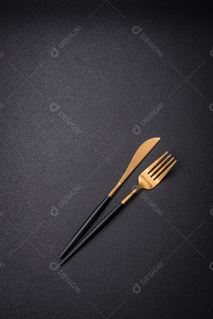Faca e garfo de cozinha feitos de aço em um fundo escuro de concret