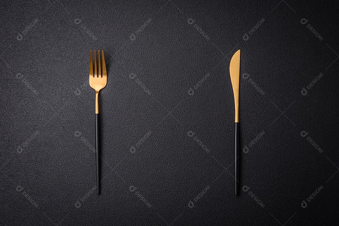 Faca e garfo de cozinha feitos de aço em um fundo escuro de concreto