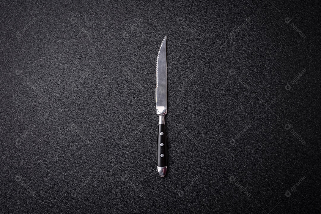 Faca e garfo de cozinha feitos de aço em um fundo escuro de concreto