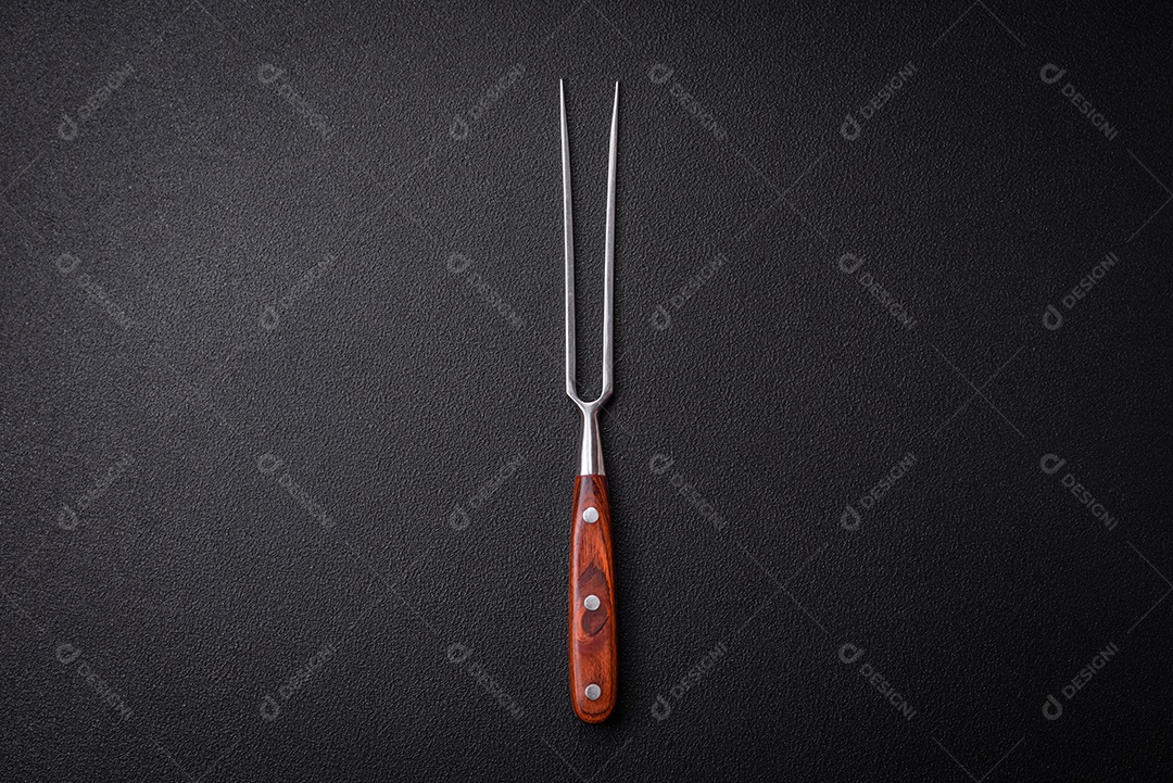 Faca e garfo de cozinha feitos de aço em um fundo escuro de concreto