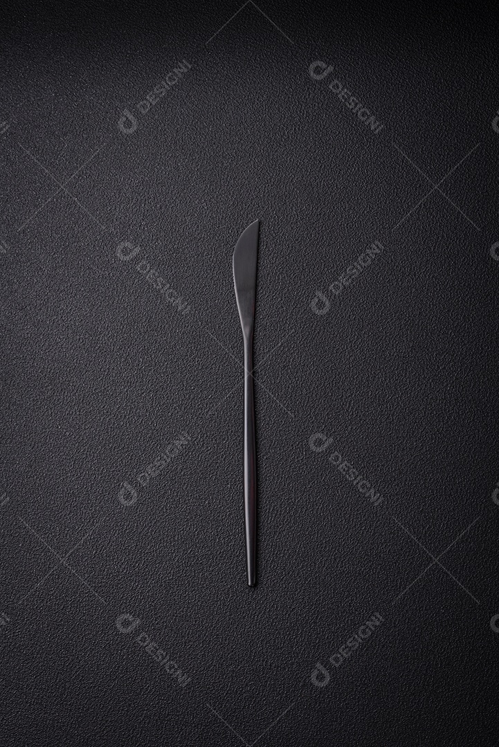 Faca e garfo de cozinha feitos de aço em um fundo escuro de concreto